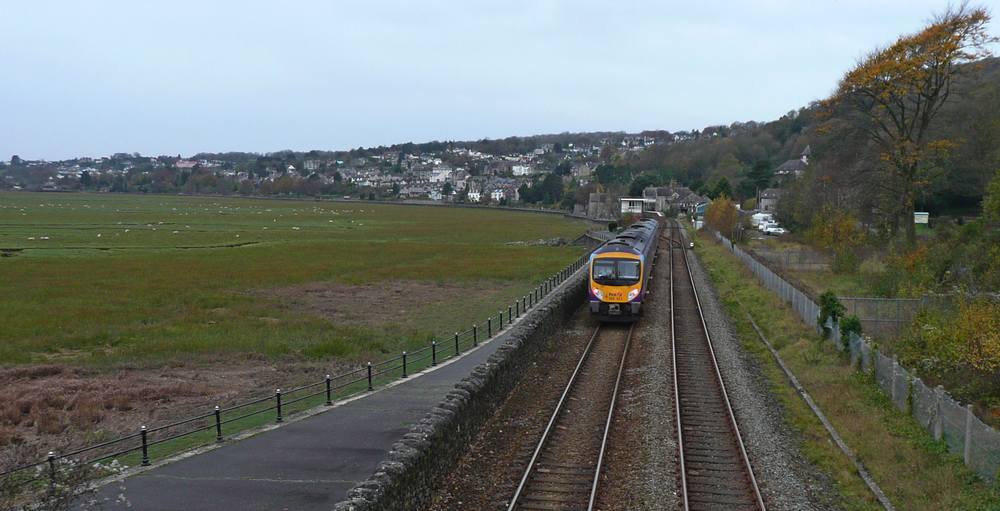 The railway line from Grange-over-Sands station with the promenade to its left and below that the sands now green and grazed by sheep